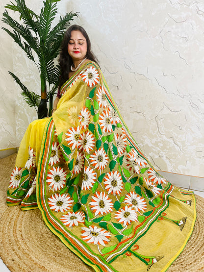 Sunflower Kantha stitch handmade sunny yellow organza saree with bold white and orange daisy blooms and green leaf embroidery — side sitting drape view, Desi Aadat