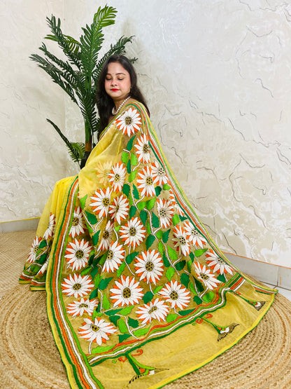 Sunflower Kantha stitch handmade sunny yellow organza saree with bold white and orange daisy blooms and green leaf embroidery — side sitting drape view, Desi Aadat