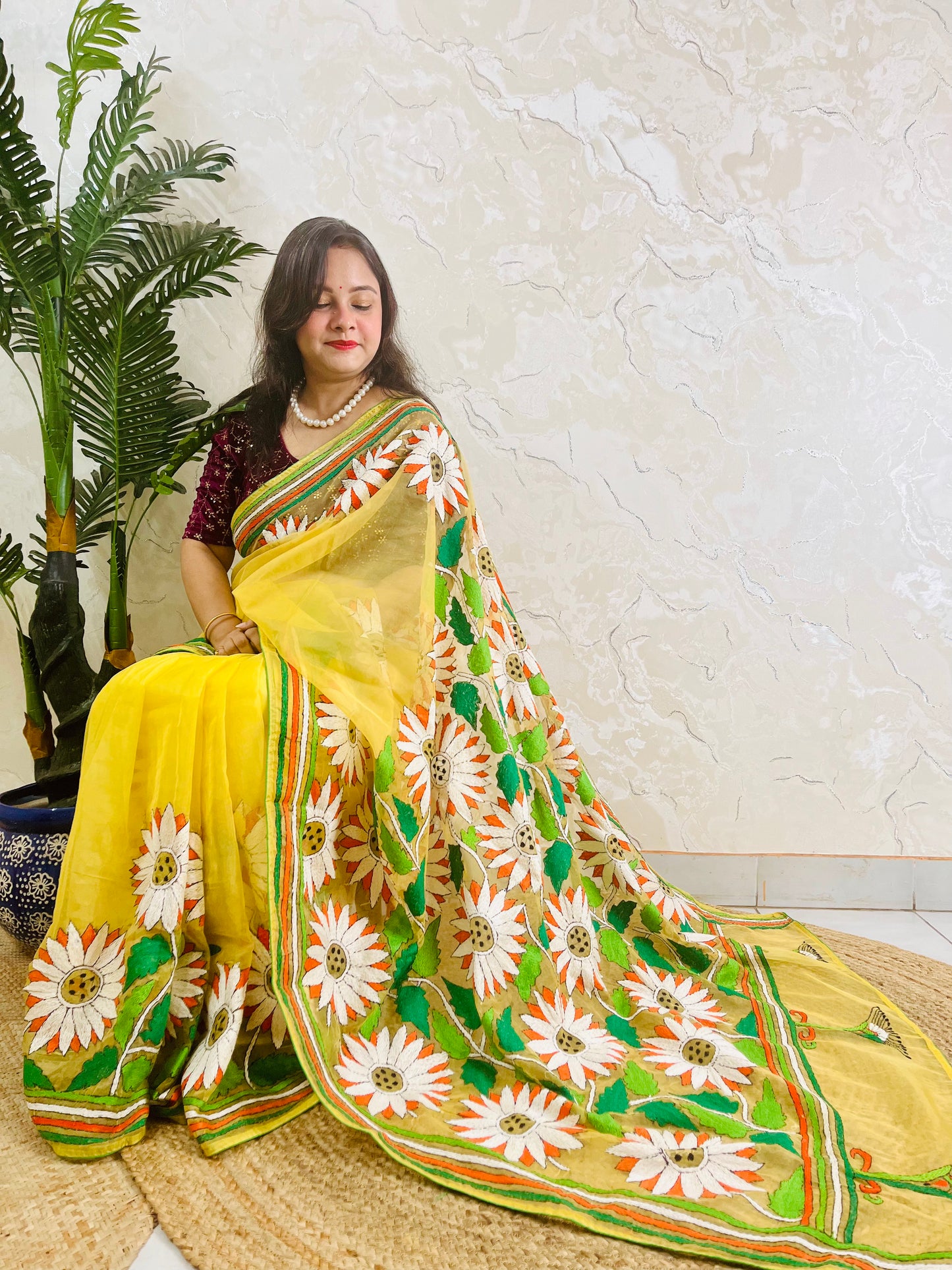 Limited edition sunny yellow Kantha stitch organza saree with all-over white sunflower embroidery and hummingbird detail — full sitting view by Desi Aadat