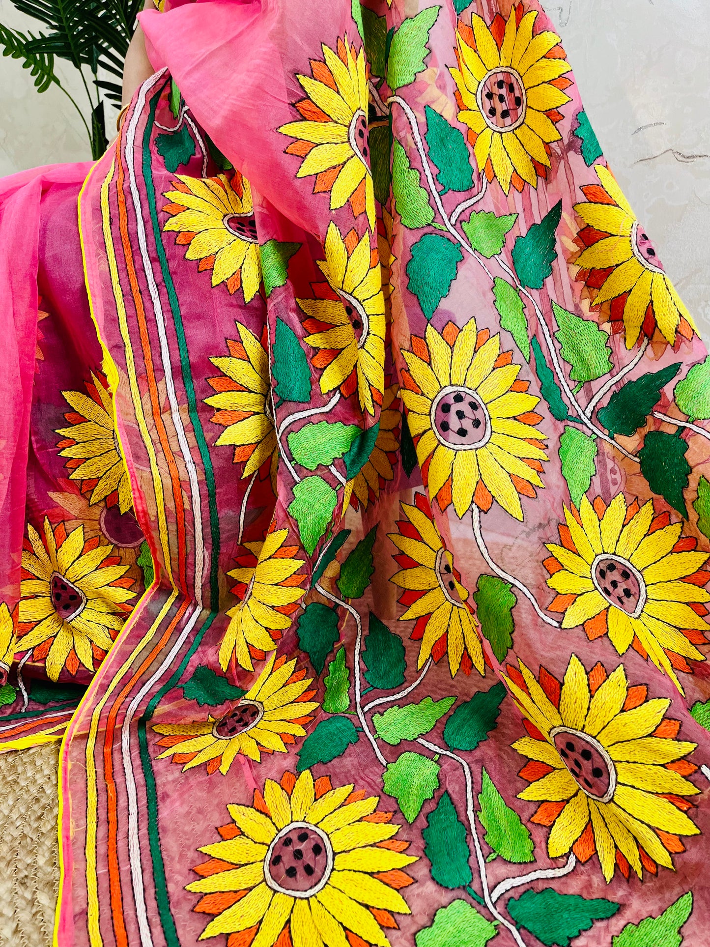 Close-up of hand-stitched Sunflower Kantha embroidery in mustard and green thread on baby pink organza saree – Desi Aadat