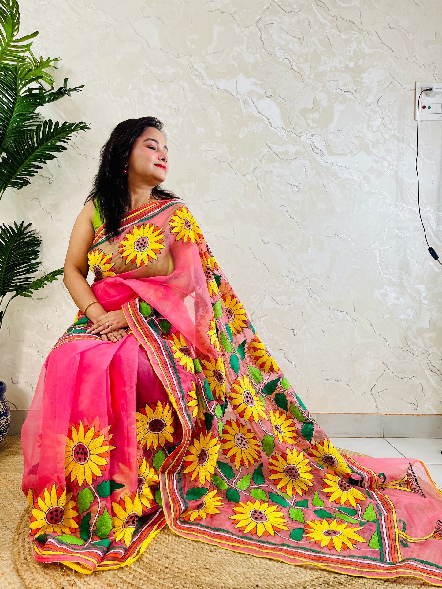 Woman seated in baby pink Kantha stitch organza saree with hand-embroidered sunflowers – Desi Aadat