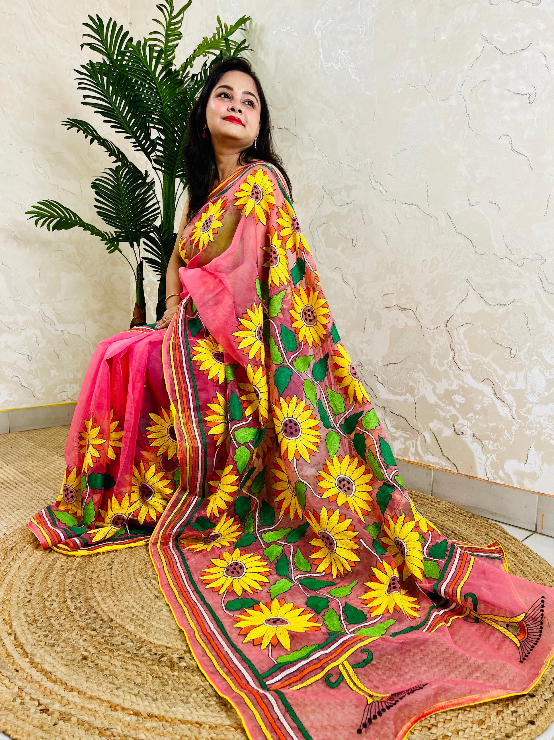 Woman seated in baby pink Kantha stitch organza saree with hand-embroidered sunflowers – Desi Aadat