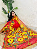 Woman seated in crimson red sunflower Kantha stitch saree, angled view