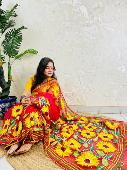 Woman seated in crimson red sunflower Kantha stitch saree, angled view