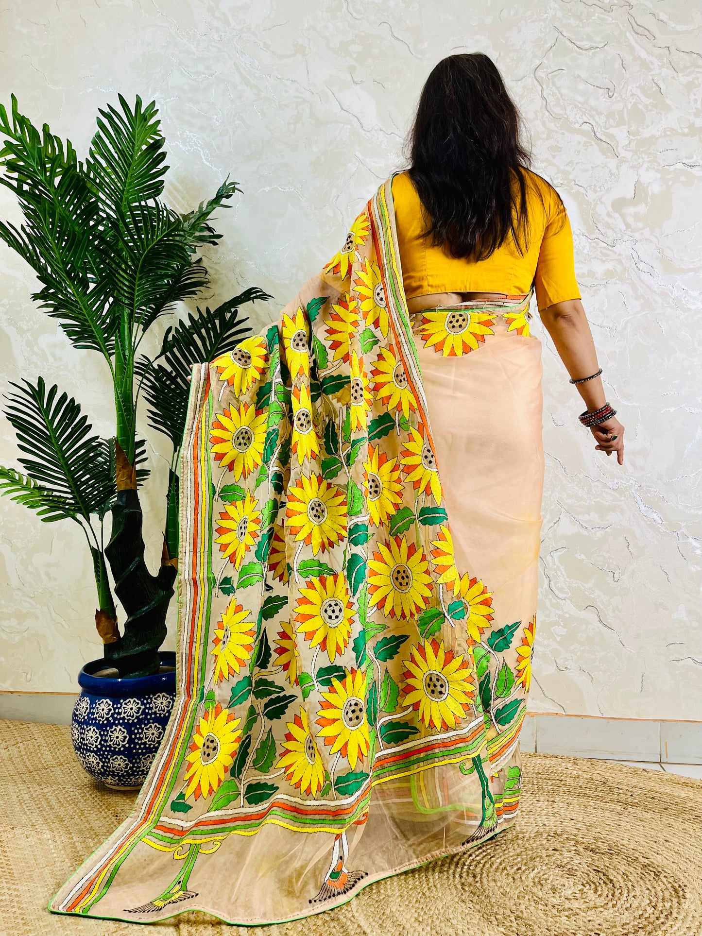 Light peach organza saree with sunflower embroidery, back standing view
