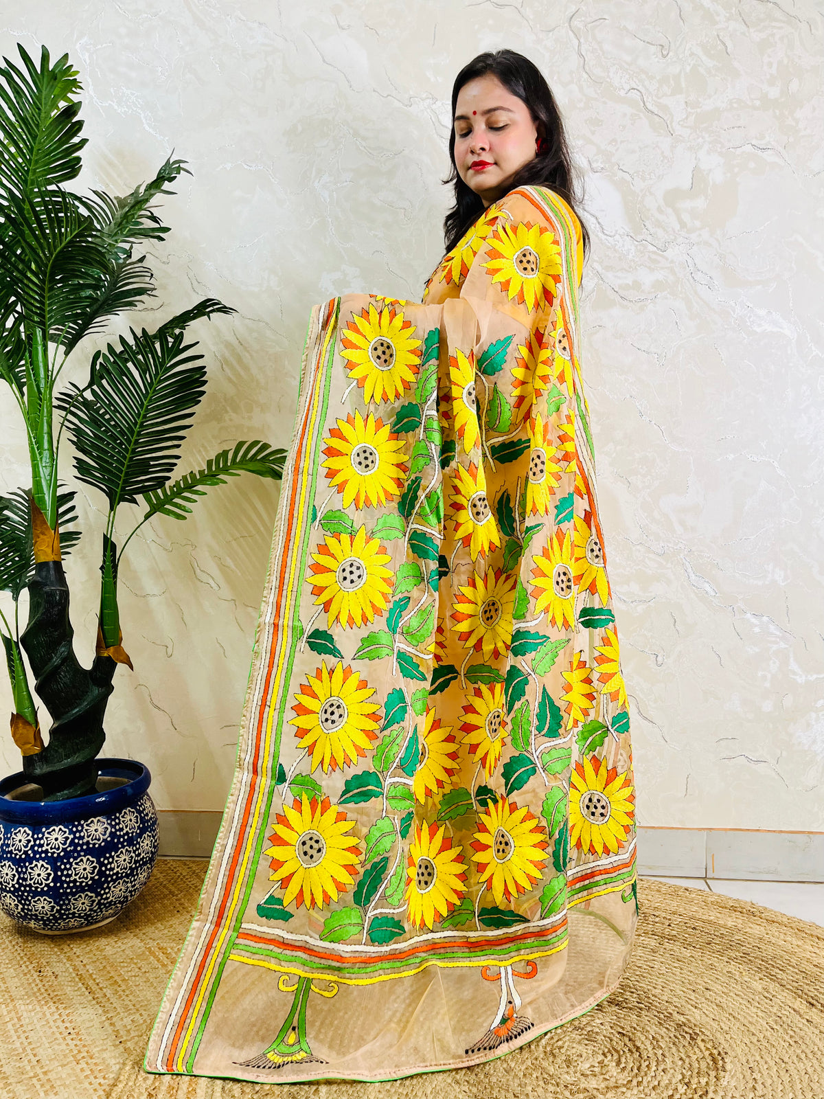 Woman standing in light peach sunflower Kantha stitch saree, side view