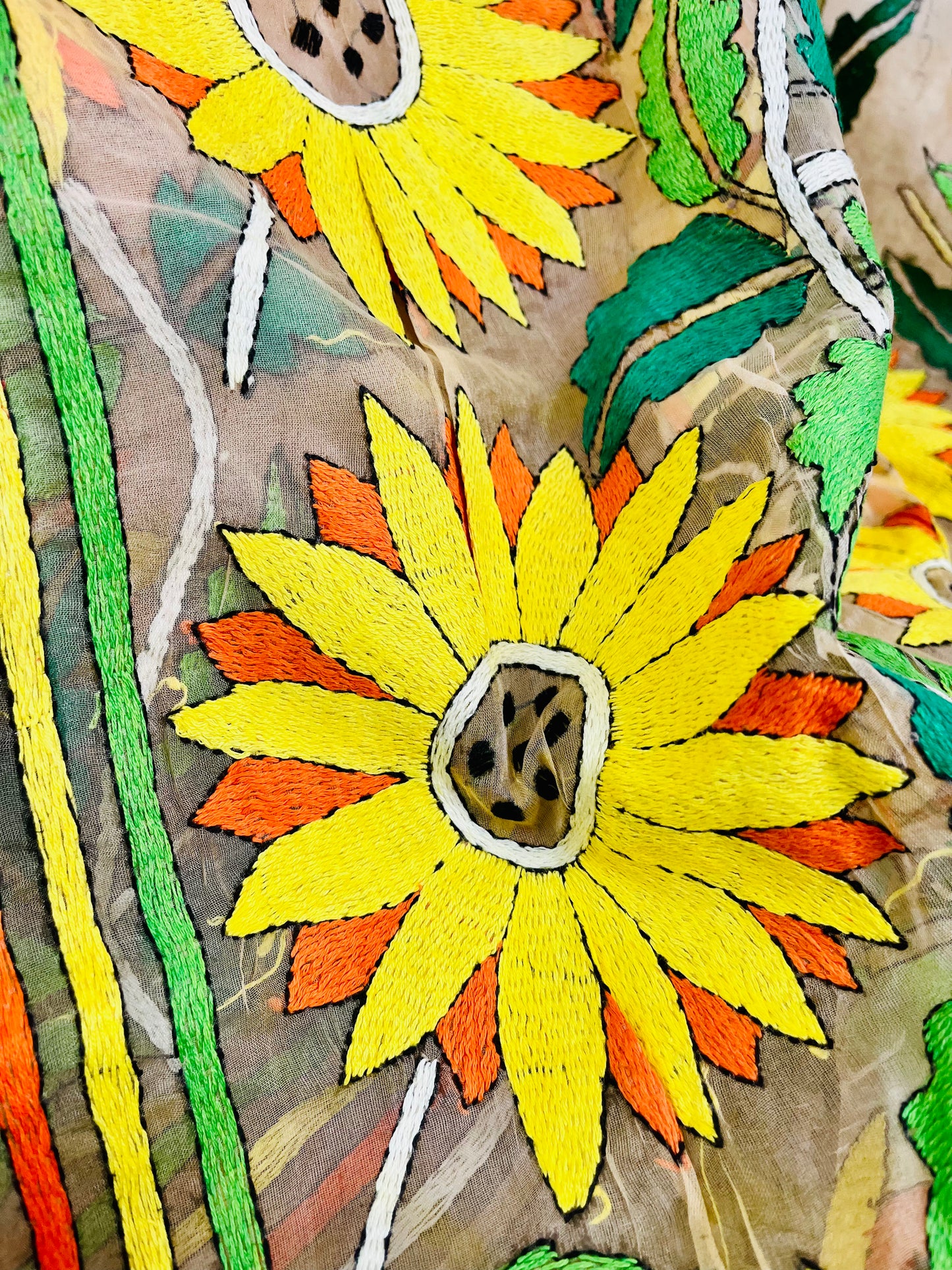 Close-up of bicolor sunflower Kantha stitch embroidery on light peach organza