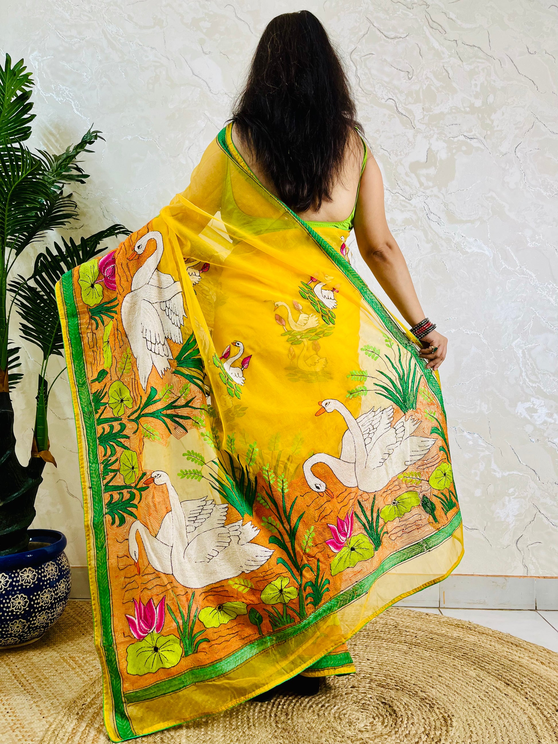 Woman in sunshine yellow swan lotus Kantha saree, back standing pose