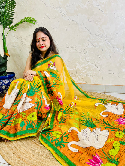 Woman seated in sunshine yellow organza saree with swan embroidery