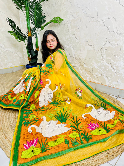 Woman seated in sunshine yellow organza saree with swan embroidery