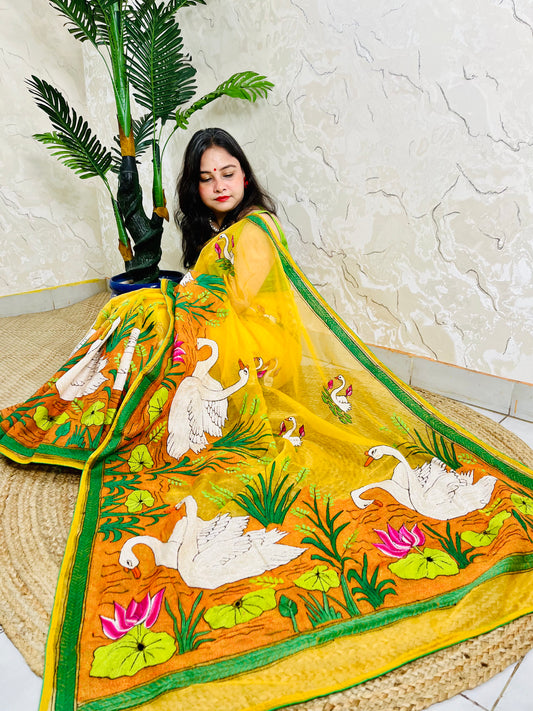Woman seated in sunshine yellow organza saree with swan embroidery