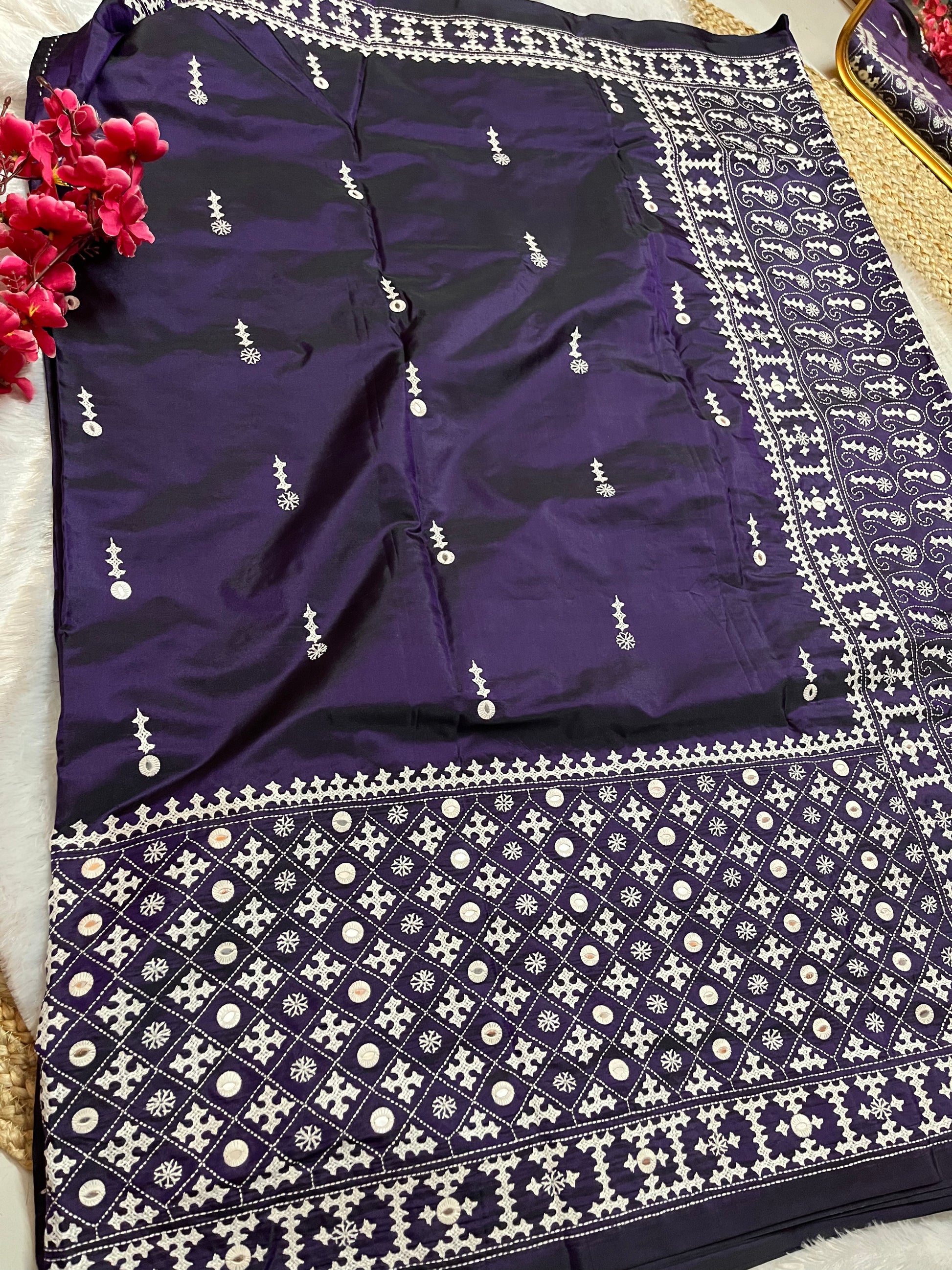 Close-up of geometric patterns, floral motifs, and mirror work on violet handwoven fabric