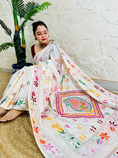 Woman seated in white Kantha stitch saree with paisley pallu spread out
