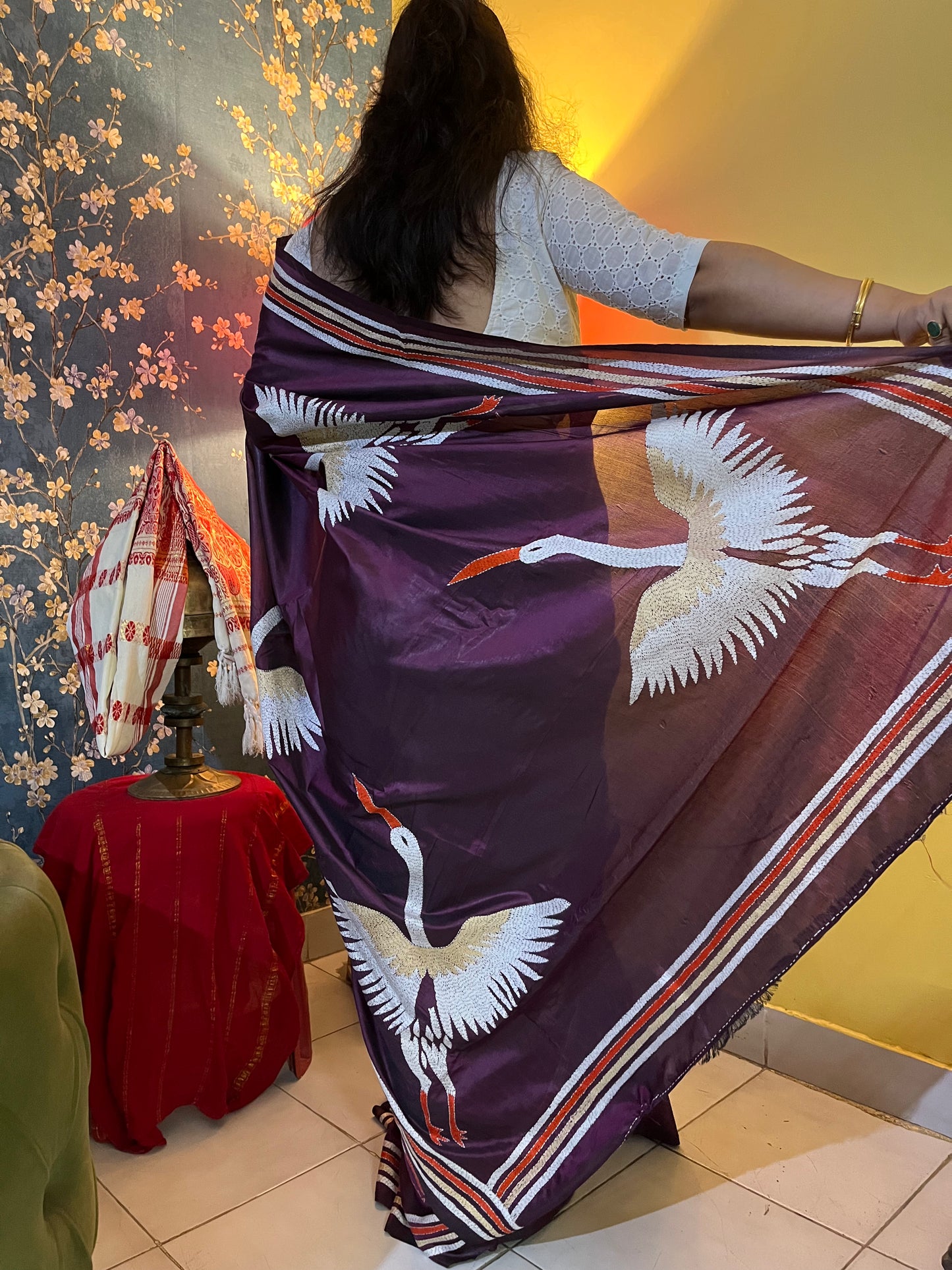 Close-up of handcrafted kantha stitch embroidery showing crane motifs on wine fabric