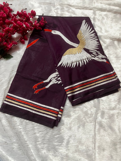 Close-up of handcrafted kantha stitch embroidery showing crane motifs on wine fabric