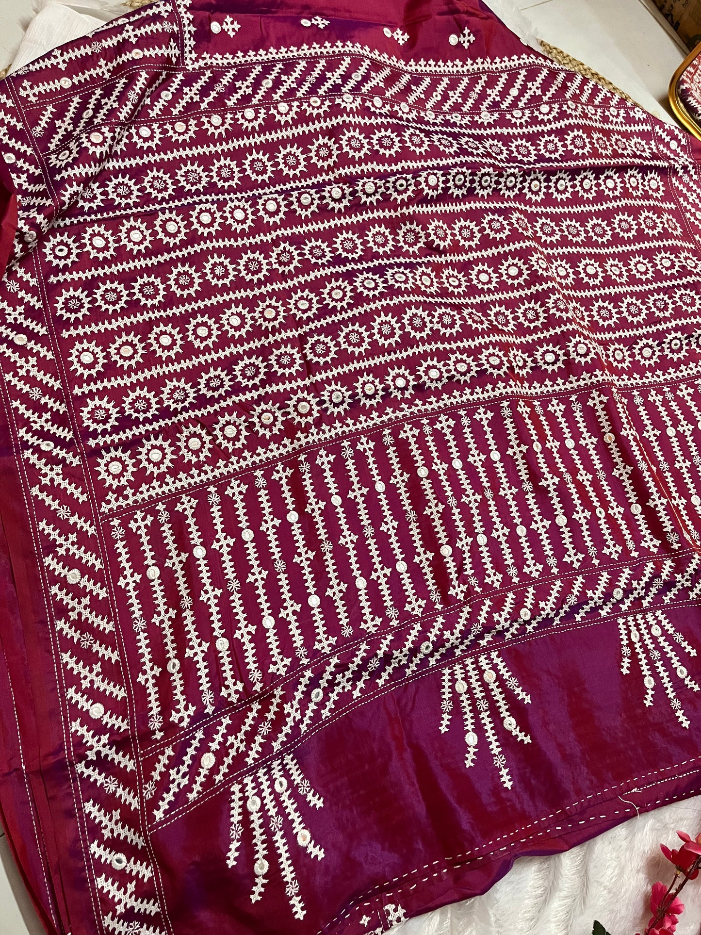 Close-up of mathematical geometric patterns and structured mirror work on wine red Bangalore silk fabric