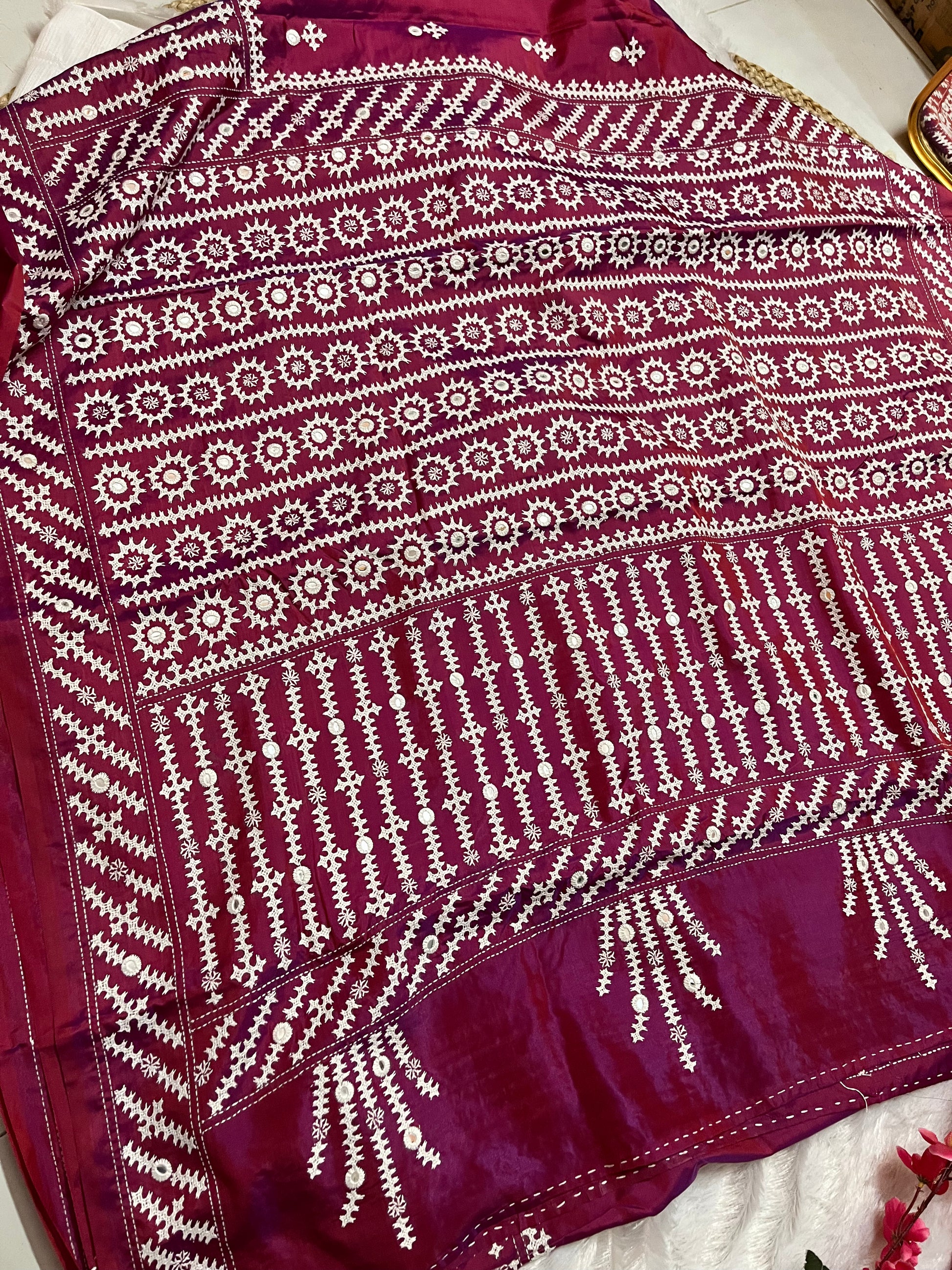 Close-up of mathematical geometric patterns and structured mirror work on wine red Bangalore silk fabric