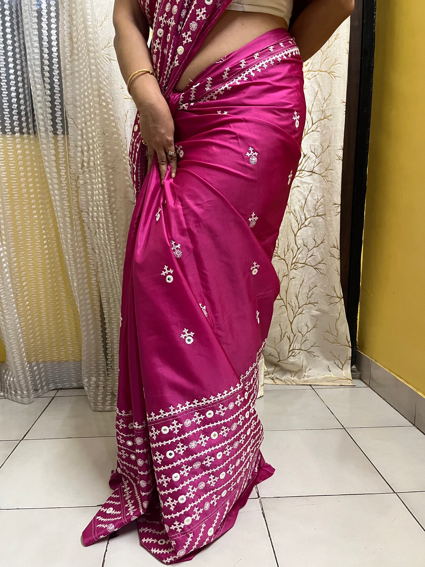 A model wearing a Burgundy Gujarati Stitch Saree with authentic Kutch hand embroidery and royal mirror work showcasing lower part of saree by Desi Aadat