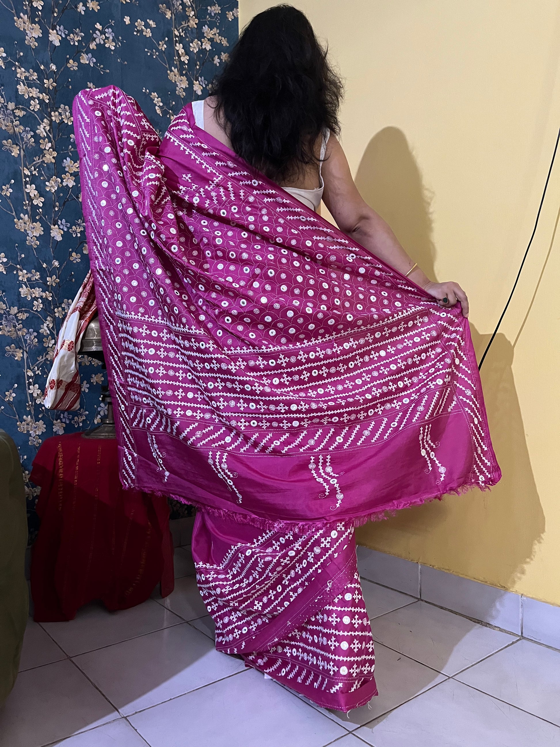 A model wearing a Burgundy Gujarati Stitch Saree with authentic Kutch hand embroidery and royal mirror work showcasing back side by Desi Aadat