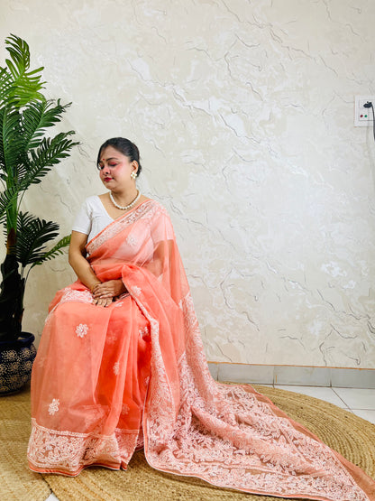 Handmade Lucknowi Chikankari pastel coral peach pure organza silk saree with tone-on-tone jaal and floral embroidery — side sitting drape view, Desi Aadat